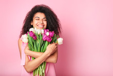Young African Woman With Flowers On Pink Background. Women's Day Concept