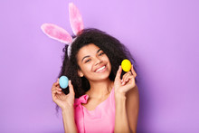 Young African Woman With Rabbit Ears And Eggs Against Purple Background. Easter Concept