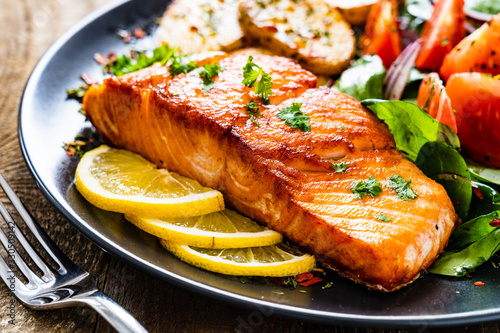 Fotomural Fried salmon steak with potatoes and vegetables on wooden table