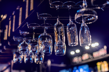 Wine and martini glasses in shelf above a bar rack in restaurant.