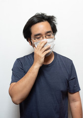 Male Asian patient wearing surgical mask feeling sick headache and coughing isolated on white background.Wuhan coronavirus (COVID-19) outbreak prevention. Health care concept