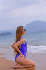 Wall Mural - Beautiful slim girl in a blue swimsuit on the ocean.