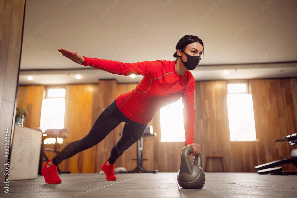 Sport Girl In Mask from Coronavirus doing Kettlebells Planking. - obrazy, fototapety, plakaty 