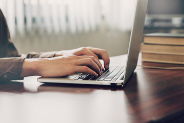 business man hand texting laptop on wooden table