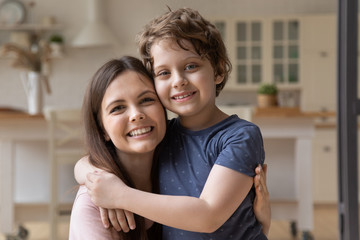 close up portrait of smiling young mom and little preschooler son embrace look at camera posing at h