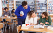 © JackF - Male teacher working with young female students in university library