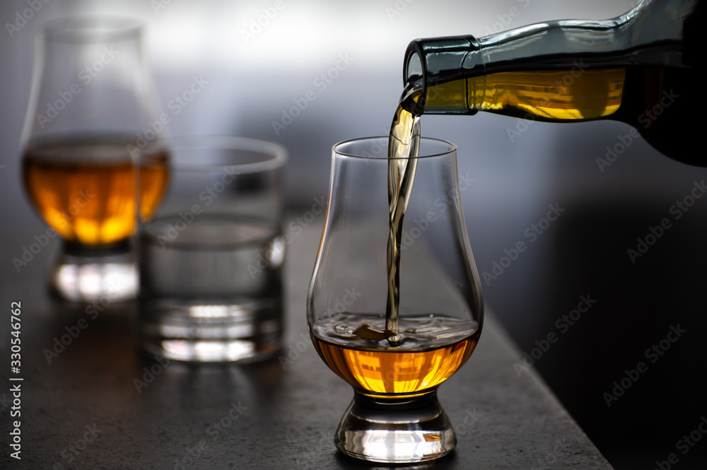 Pouring in tulip-shaped tasting glass Scotch single malt or blended whisky - obrazy, fototapety, plakaty 