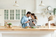 © fizkes - Happy loving couple holding wine glasses, touching foreheads, enjoying tender moment, romantic date, standing in modern kitchen at home together, smiling wife and husband celebrating anniversary