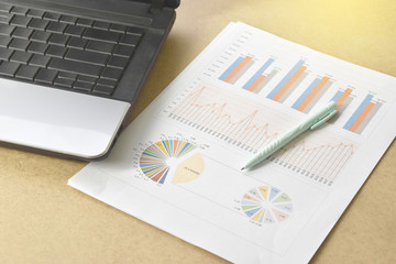 Financial graphs and charts with eyeglasses, calculator on desk.