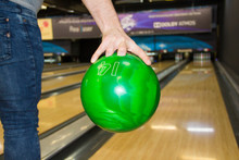 A Man 's Hand Holding A Bowling Ball Close. A Man's Hand Throws A Bowling Ball Close-up, A Man Playing Bowling Against The Background Of The Playing Field