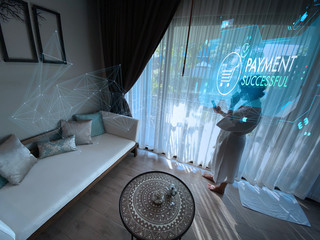 Poster - Woman in white bathrobe siting on the armchair near the window in hotel room using smartphone for online payment and banking and online shopping.