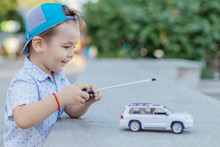 A Small Boy Plays With A Toy Car On Radio Control Holding A Remote Control