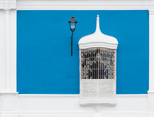 Blue colonial style facade with wrought or cast iron window and lamp post, Trujillo, Peru.