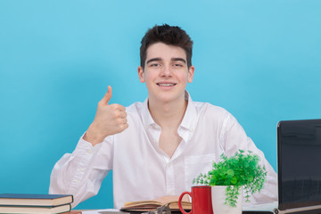 Poster - student at the desk isolated on color background at the table with books and school supplies