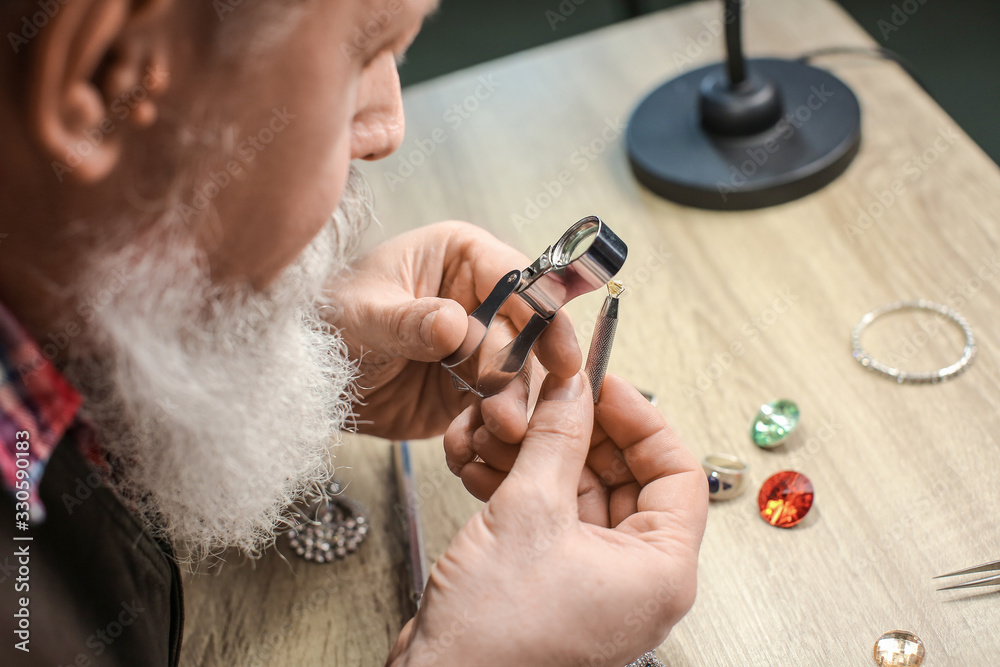 Jeweller examining gemstone in workshop, closeup