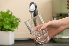 Woman Filling Glass With Fresh Water From Kitchen Faucet