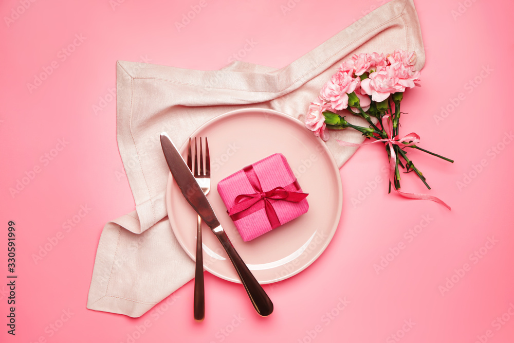 Beautiful table setting with gift and flowers on color background