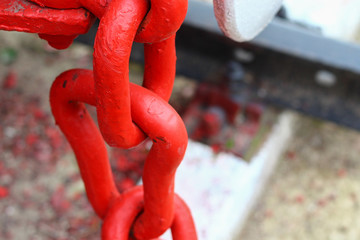 Link element of a chain of red color, massive metal, background