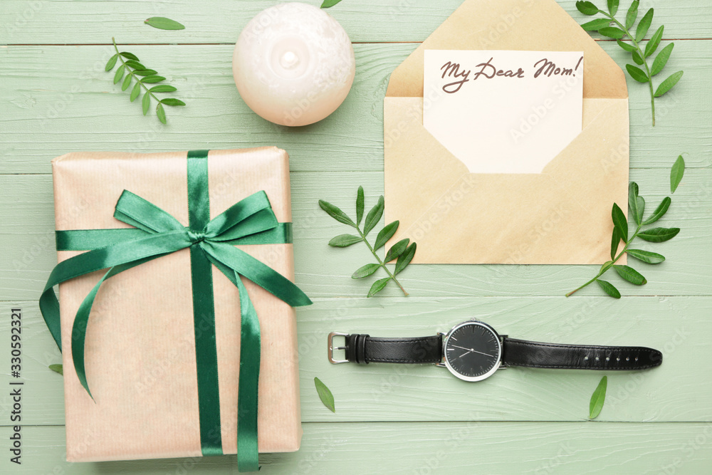 Composition with greeting card for mother, envelope and gift on wooden background