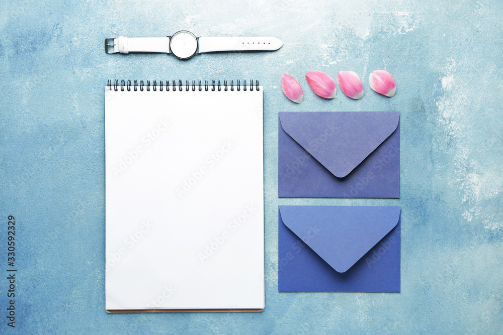 Envelopes with notebook and clock on color background