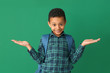 Cute African-American schoolboy on color background