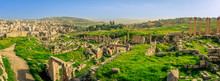 Panorama Overview Of The Roman Site Of Gerasa, Jerash, Jordan, With Ruins, Pillars And Remains Of The Old City Clearly Visible. Green Grass And Blue Sky On A Sunny Day In Spring. 