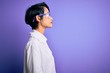 © Krakenimages.com - Young beautiful asian scientist girl wearing coat and glasses over purple background looking to side, relax profile pose with natural face with confident smile.