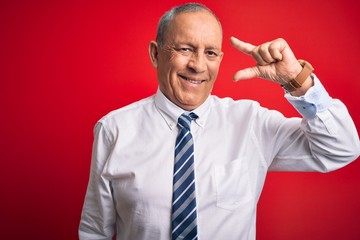 Sticker - Senior handsome businessman wearing elegant tie standing over isolated red background smiling and confident gesturing with hand doing small size sign with fingers looking and the camera. Measure