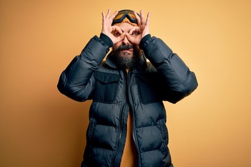 Poster - Handsome skier bald man with beard skiing wearing snow sportswear and ski goggles doing ok gesture like binoculars sticking tongue out, eyes looking through fingers. Crazy expression.