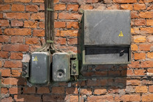 Old Rusty Electrical Panel With Buttons And Wires On A Ragged Red Brick Wall Of A Factory