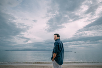 Wall Mural - A lonely man walks along the beach on a cloudy day