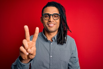 Young handsome african american man with dreadlocks wearing casual shirt and glasses showing and pointing up with fingers number two while smiling confident and happy.