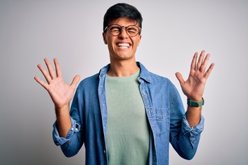 Young handsome man wearing casual shirt and glasses over isolated white background celebrating mad and crazy for success with arms raised and closed eyes screaming excited. Winner concept