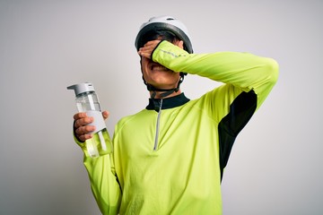 Poster - Young handsome cyclist man wearing security bike helmet drinking bottle of water stressed with hand on head, shocked with shame and surprise face, angry and frustrated. Fear and upset for mistake.