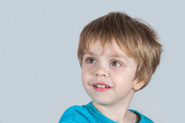 Child looking carefully with interest and smiling. Light background. Closeup (concept human behavior)