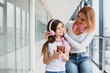 © Serhii - Happy young mother and her daughter walking in the airport terminal while carrying a suitcase. High season and vacation concept. Relax and lifestyles