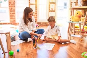 Poster - Beautiful teacher and toddler drawing using pencils and paper around lots of toys at kindergarten