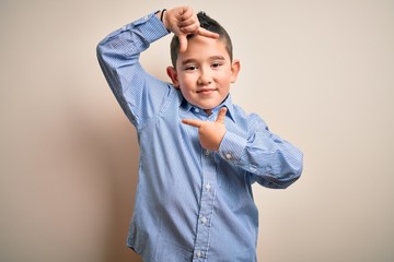 Poster - Young little boy kid wearing elegant shirt standing over isolated background smiling making frame with hands and fingers with happy face. Creativity and photography concept.