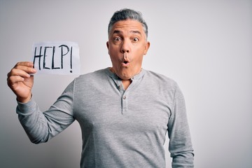 Poster - Middle age handsome grey-haired man holding paper with help message scared in shock with a surprise face, afraid and excited with fear expression