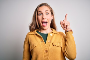 Wall Mural - Young beautiful blonde woman wearing casual sweater over isolated white background pointing finger up with successful idea. Exited and happy. Number one.