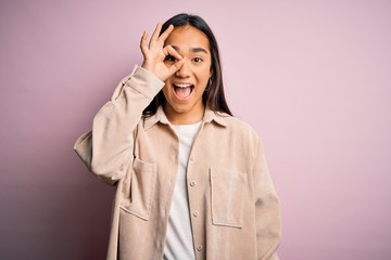 Poster - Young beautiful asian woman wearing casual shirt standing over pink background doing ok gesture with hand smiling, eye looking through fingers with happy face.