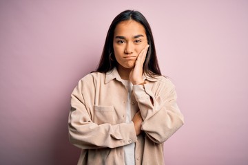 Poster - Young beautiful asian woman wearing casual shirt standing over pink background thinking looking tired and bored with depression problems with crossed arms.