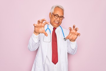 Wall Mural - Middle age senior grey-haired doctor man wearing stethoscope and professional medical coat smiling funny doing claw gesture as cat, aggressive and sexy expression