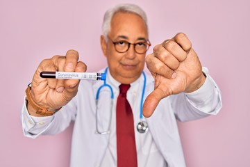 Canvas Print - Middle age senior doctor holding medice blood sample of coronavirus infection disease with angry face, negative sign showing dislike with thumbs down, rejection concept