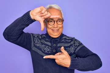 Poster - Middle age senior grey-haired man wearing glasses and winter sweater over purple background smiling making frame with hands and fingers with happy face. Creativity and photography concept.