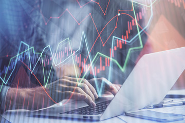 Double exposure of market chart with man working on computer on background. Concept of financial analysis.