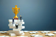 Miniature business concept - businessman standing on white staircase ladder with golden trophy above it