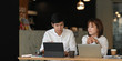 © Prathankarnpap - Photo of graphic designer team working together with computer laptop and tablet while sitting at the wooden working table over the modern restaurant as background.