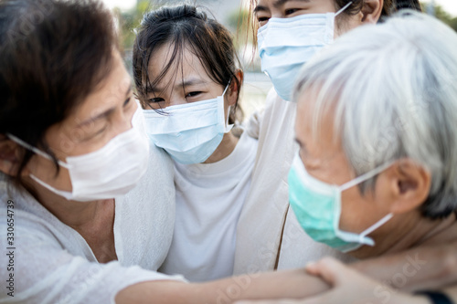 Sad asian family wearing medical mask crying,suffer from grief,great loss of her family infected,fight the Covid-19,Coronavirus outbreak,people affected epidemic crisis ,hug,comforting,encouragement