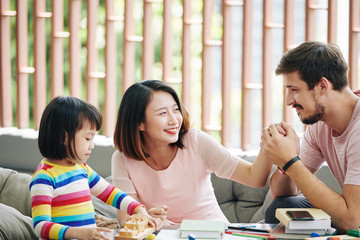 Wall Mural - Happy young man enjoying spending time with his wife and daughter